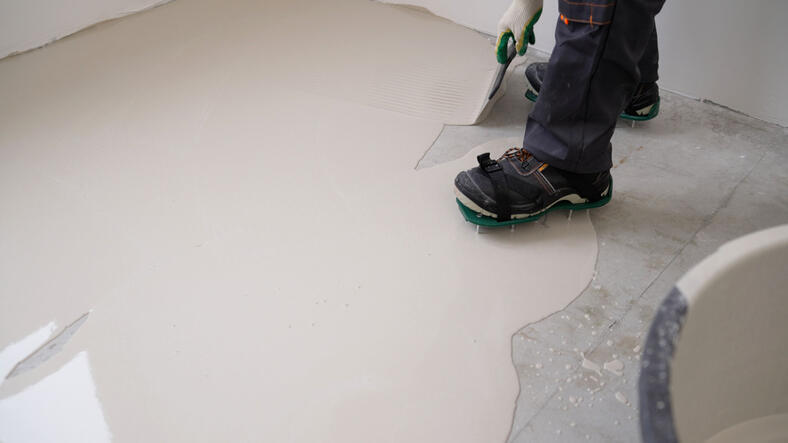 Spreading self leveling compound with trowel. Self leveling epoxy. Leveling with a mixture of cement floors. Leveling liquid floors with a trowel